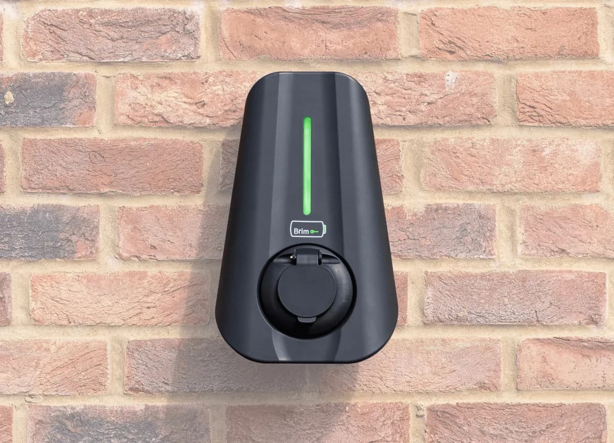 Black Brim wallbox with a green status light and closed charging socket on a brick wall